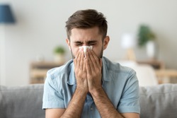 Ill young man sneezing in handkerchief blowing wiping running nose, sick allergic guy caught cold got flu influenza hay fever coughing, having seasonal allergy symptoms respiratory contagious disease