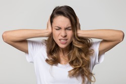 Annoyed stressed woman cover ears feel hurt ear ache pain otitis suffer from loud noise sound headache, irritated stubborn girl deaf hear not listen to noisy music isolated on white studio background