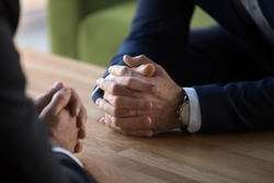 Clasped male hands of two businessmen negotiate at table, hr recruiter making hiring decision at difficult job interview, opponents dialogue debate, business confrontation challenge concept, close up