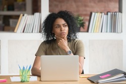 Thoughtful concerned african american female worker student feeling uncertain bored doubtful solving problem at work with laptop, puzzled black businesswoman looking away thinking having lack of idea