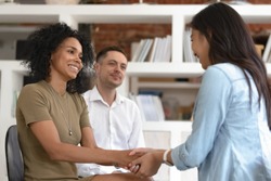 Asian and african women holding hands during group therapy session, diverse friends feeling reconciled relief smiling giving psychological support empathy overcome problem at psychotherapy counseling