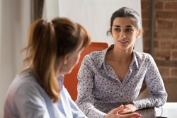 Indian businesswoman speaking to colleague or hr during job interview, young professional hindu woman manager consulting client or explaining giving advice teaching at business office meeting