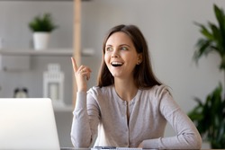 Young happy woman sitting at desk near laptop gesturing with hand make finger up, feels excited with good idea reach inspiration motivation, found solution for success at work or study, eureka concept