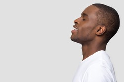 Side profile african male standing on grey background aside copyspace for your advertisement text. Positive american guy closed eyes enjoy fresh air make deep breath, dreaming feels peaceful concept