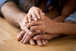 Close up of loving family stack hands on warm floor together show support and unity, caring parents join arms with child express devotion loyalty understanding. Bonding, good relationships concept