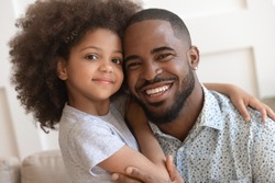 Happy affectionate african american family young daddy and small cute child daughter portrait, loving black dad and little mixed race kid girl bonding embrace looking at camera on fathers day concept