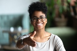 Happy african American young woman in glasses stretch hand for handshake greeting introducing to someone, smiling black biracial millennial female hr agent in spectacles get acquainted at meeting