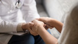 Close up horizontal image doctor in white uniform holding hands of female patient, showing support, gave professional aid psychological help, disease express of empathy and trusted specialist concept