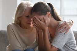 Worried aged mother embracing comforting grown up daughter with broken heart family sit on sofa, elderly mom soothe crying adult child, divorce or miscarriage, share problem with someone close concept