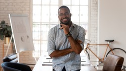 Happy african american businessman entrepreneur startup owner stand in modern office looking at camera, smiling young black designer creative occupation person posing in work space, business portrait