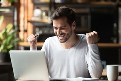 Excited overjoyed young business man student winner looking at laptop celebrate bet bid win online success victory new opportunity sit at cafe table, read good internet email news, got new job offer