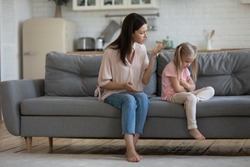 Angry mother scolding little daughter people sitting on couch, parent teaches a naughty mischievous child, kid girl feels upset about punishment deprivation of entertainment due to misconduct concept