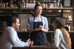 Smiling waitress wear apron hold notepad pen take order talk to clients serving restaurant guests couple choosing food drinks menu sit at cafe coffeehouse table, waiting staff, good customer service