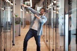 Overjoyed funny male employee have fun perform winner dance in modern office hallway, excited happy millennial businessman celebrate business success or promotion, Friday evening, end of working week
