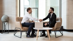 Horizontal view european and arabian businessmen in formal wear accomplish meeting shaking hands feels satisfied after negotiations, HR manager greeting applicant before job interview process concept