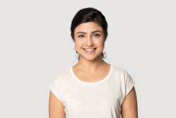Headshot portrait of happy indian millennial girl stand isolated on grey studio background wear t-shirt look at camera, smiling ethnic young woman posing showing white healthy teeth, dental treatment
