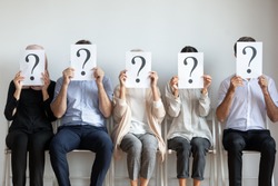 Unemployed professional business people candidates group sit on chairs in row line queue holding sheets with question mark hiding face waiting for job interview, human resources and recruit concept