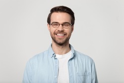 Happy millennial Caucasian guy wear glasses isolated on grey studio background smiling with white healthy teeth, positive young man in casual clothes posing look at camera show good treatment result