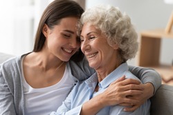 Positive smiling old grandma mother and young adult granddaughter daughter bonding at home, happy two generation women family laughing hugging having fun enjoying time together at reunion meeting