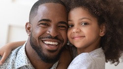 Close up portrait african five or six years old daughter cuddles handsome loving cheerful father relative people posing for camera smiling feels happy being together, daughterhood fatherhood concept