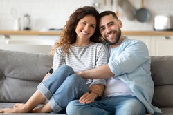 Portrait of young 35s just married couple in love posing photo shooting seated on couch in modern studio apartments, concept of capture happy moment, harmonic relationships, care and sincere feelings