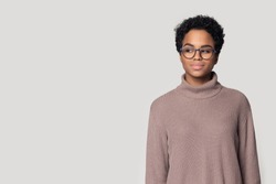 African girl wearing knitted jumper and glasses pose aside on gray studio background looking sideways on copy space for advertisement text, eyeglasses or accessories fashion store promotion ad concept