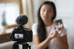 Close up of professional video camera shooting young Asian beauty blogger make unpacking product at home, camcorder device record millennial influencer or vlogger broadcast advertising content