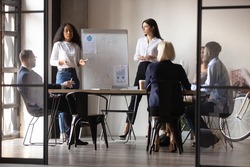 Diverse women startupper mixed-race and european ethnicity make perform presentation for investors during meeting at office boardroom, staff listening coaches attending at educational training concept