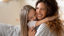 Cute little girl hug cuddle excited young mum show love and affection, smiling mother and funny small preschooler daughter have fun at home embrace sharing close tender moment together