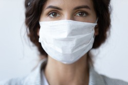 Close up portrait of beautiful 30s young millennial woman cover her face wearing facial medical blue mask, anti-coronavirus COVID-19 pandemic infectious disease outbreak protection, healthcare concept