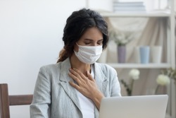 Business woman in mask sitting at desk feels unhealthy put hand where is lungs, suffering from repeated coughing and breath difficulties. Risk coronavirus 2019-ncov contamination at workplace concept