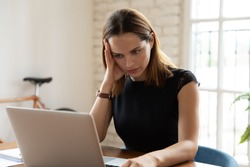 Overloaded woman sit at workplace desk touch head feels unwell suffers from headache migraine, businesswoman read unpleasant news, dismissal message, notebook broken malware, problems at work concept