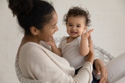Loving young african American mother hold embrace cute little ethnic infant toddler, caring biracial mom play have fun hug small baby child, enjoy family time at home together, childcare concept