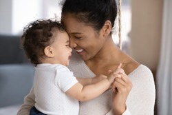 Close up of happy young african American mother hug cuddle little infant or toddler, loving smiling biracial mom embrace small baby child, enjoy tender family moment, motherhood, childcare concept