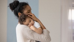 Caring young biracial mother hold lean to chest cute little infant toddler, loving african American mom hug embrace small baby child, relax enjoy tender family moment at home, childcare concept