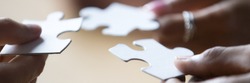 Close up photo hands of multi ethnic people hold diverse pieces of puzzle, team assembling jigsaw joining fragments, teamwork, search find solution concept. Horizontal banner for website header design