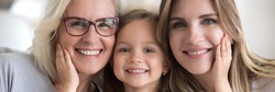 Little girl her young mother and mature grandma portrait. Multi generational women faces smiling looking at camera close up view photo, family bond concept. Horizontal banner for website header design