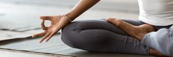African woman wearing active wear do yoga practice meditating indoors, close up cropped photo lotus position. No stress, mindfulness, inner balance concept. Horizontal banner for website header design