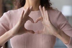 Close up young woman showing heart gesture with fingers, expressing love, support and care, gratitude, regular medical checkup promotion, cardiovascular diseases prevention, charity concept