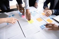 Close up table full of papers, diverse businesspeople analyzing report in charts and graphs discuss paperwork data statistics at group meeting. Research overview activity, brainstorm teamwork concept