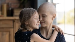 Happy young Caucasian cancer patient sick mother and little daughter hug show love and care, supportive small girl child embrace caress ill hairless mom suffer from oncology, feel grateful thankful