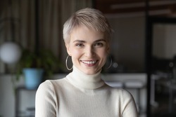 Head shot profile portrait of young happy short haired blonde businesswoman in modern office. Smiling 30s female manager, talented corporate employee, confident saleswoman looking at camera.
