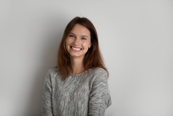 Profile picture of smiling young red-haired woman stand isolated on grey studio background show positive optimistic spirit, portrait of happy Caucasian female pose demonstrate white healthy teeth