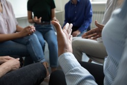 Sharing ideas. Close up view of diverse people group gathered in circle at workplace office cabinet to discuss work or self problems, share points of view, listen to mates, feel psychological support