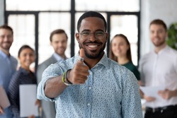 Best ever! Portrait of loyal excited black male client customer demonstrating thumb up sign recommending good product service, happy african employee looking at camera glad to work in company staff