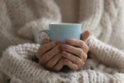 Close up mature woman wrapped warm blanket holding mug of coffee or tea, middle aged female enjoying free time, weekend at home, relaxing, drinking hot beverage in morning, starting new day