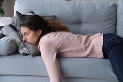 Tired unmotivated young woman falls asleep on cozy couch indoors, having no energy after hard working day. Exhausted caucasian lady napping on comfortable sofa in living room, fatigue concept.