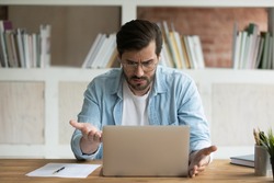 Unhappy Caucasian male employee work online on laptop in office frustrated by error or mistake on gadget. Upset mad man worker look at computer screen confused by slow internet or device breakdown.