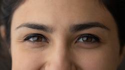 Crop close up of eyes of smiling young Indian woman look at camera feel optimistic satisfied. Closeup of happy millennial mixed race ethnicity female. Diversity, ethnic, wide view concept.