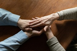 Middle aged wife holds hands of beloved mature husband. Elderly married couple of pensioners gives comfort, expresses trust, support and care. Close up of stack of arms with wedding ring. Hope concept